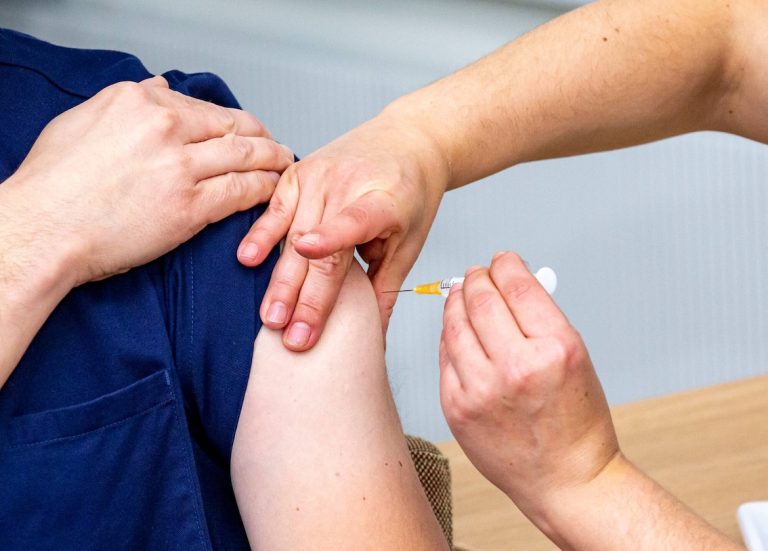 Terveydenhuollon ammattilainen antamassa rokotetta potilaan käsivarteen.