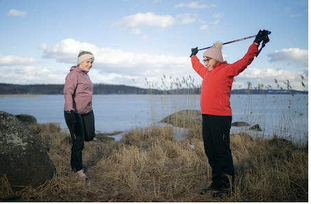 Kaksi naista venyttelemässä järven rannalla