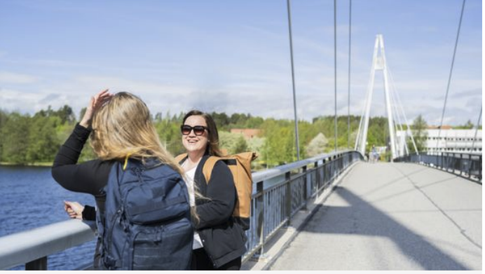 Kaksi naista seisoo auringossa sillalla