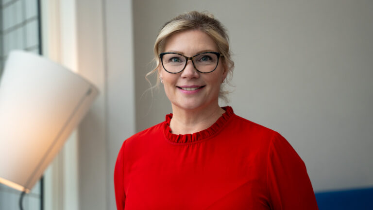 hymyilevä vaalea silmälasipäinen nainen